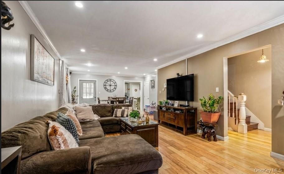 Recessed lighting, crown molding, wood-finish flooring, and a built-in entertainment console