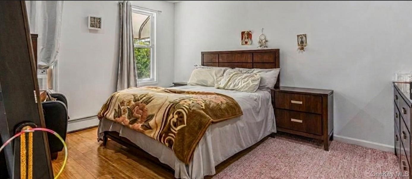 The spacious master bedroom features warm hardwood flooring, clean white walls, and a bright window that overlooks the property. The expansive layout 