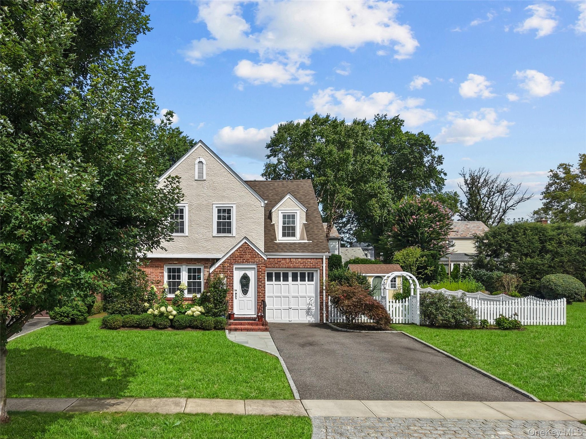 Brick and stucco exterior with a gabled roofline and four car asphalt driveway.