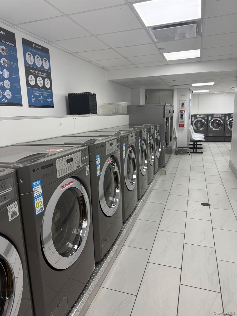 Shared laundry room featuring independent washer and dryer and light tile patterned floors