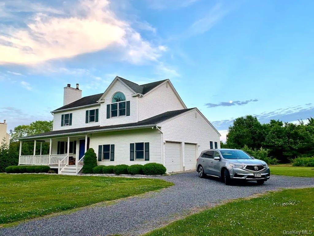 Front of House with covered front porch, attached two-car garage, and a gravel driveway