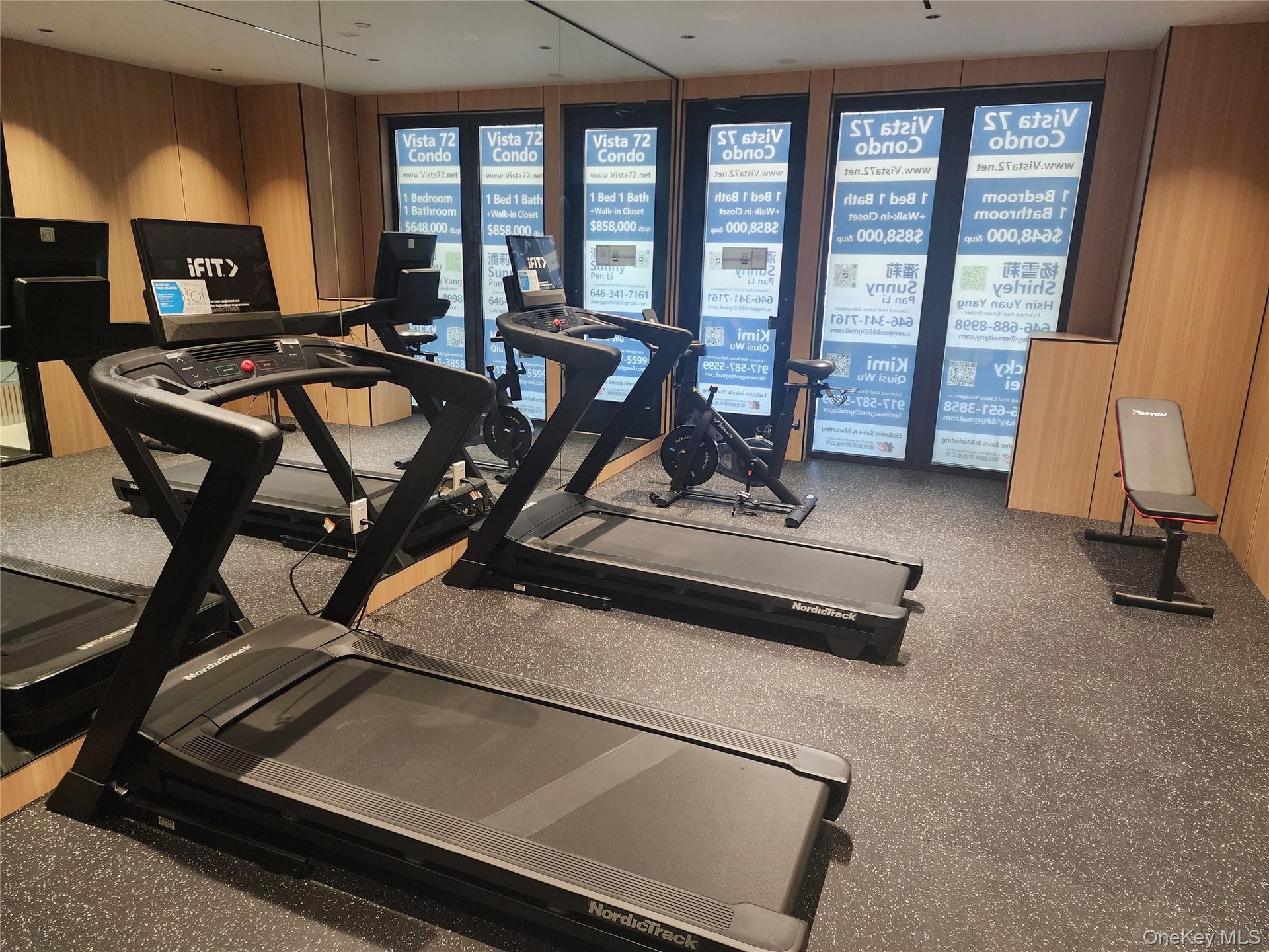 Fitness area featuring two treadmills, an exercise bike, a weight bench, and a rubberized flooring surface
