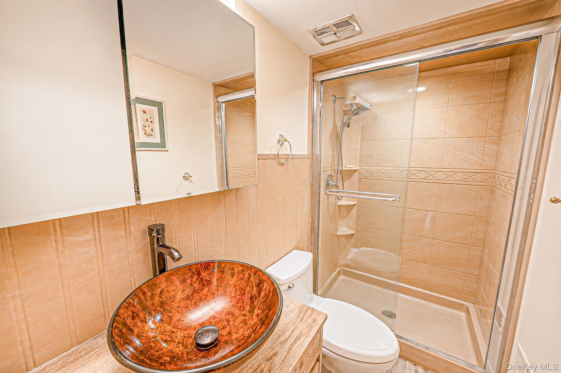 Glass-enclosed shower with tiled walls and decorative accent band