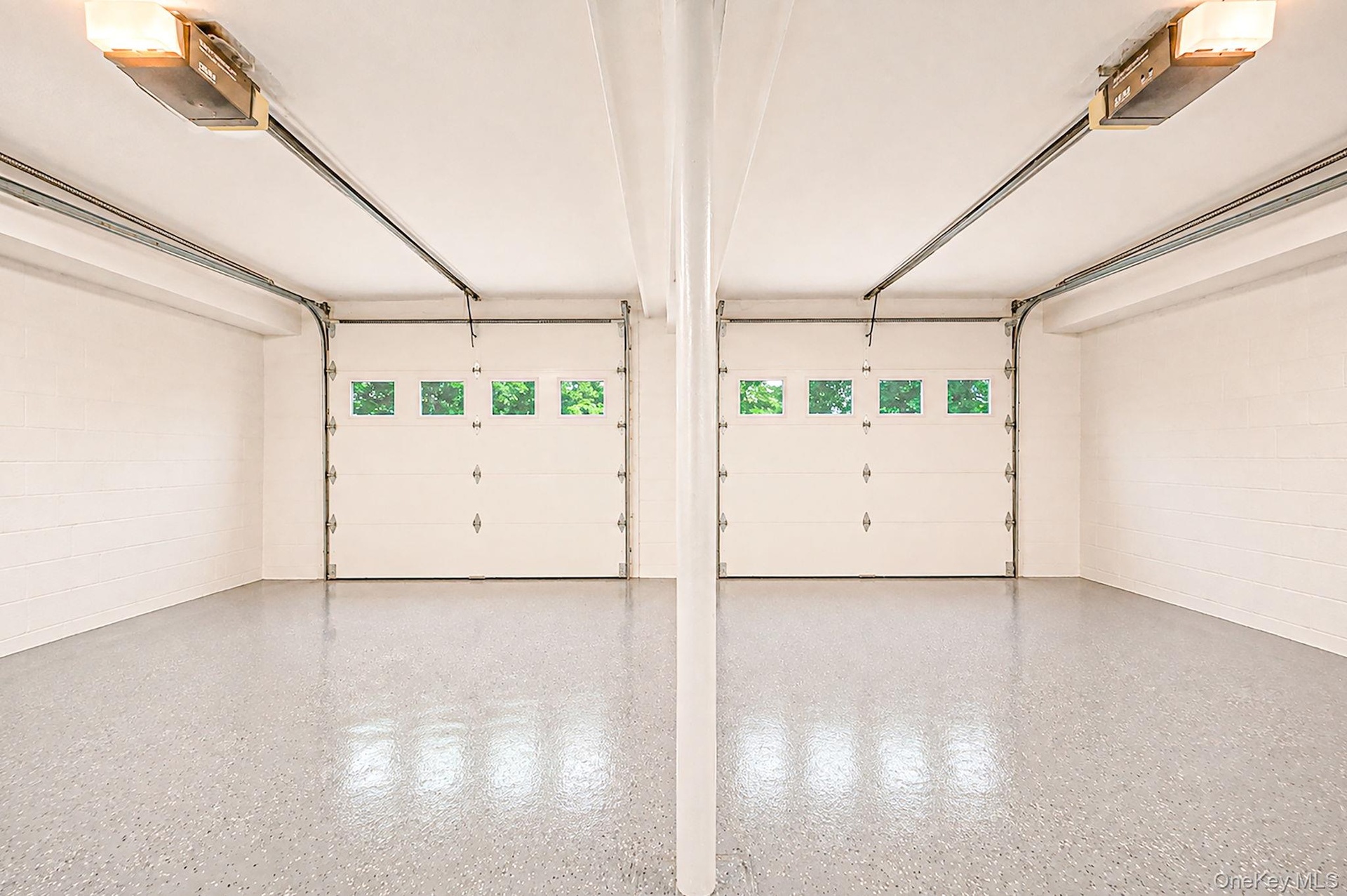 Two garage bays featuring white overhead doors with window inserts and automatic openers