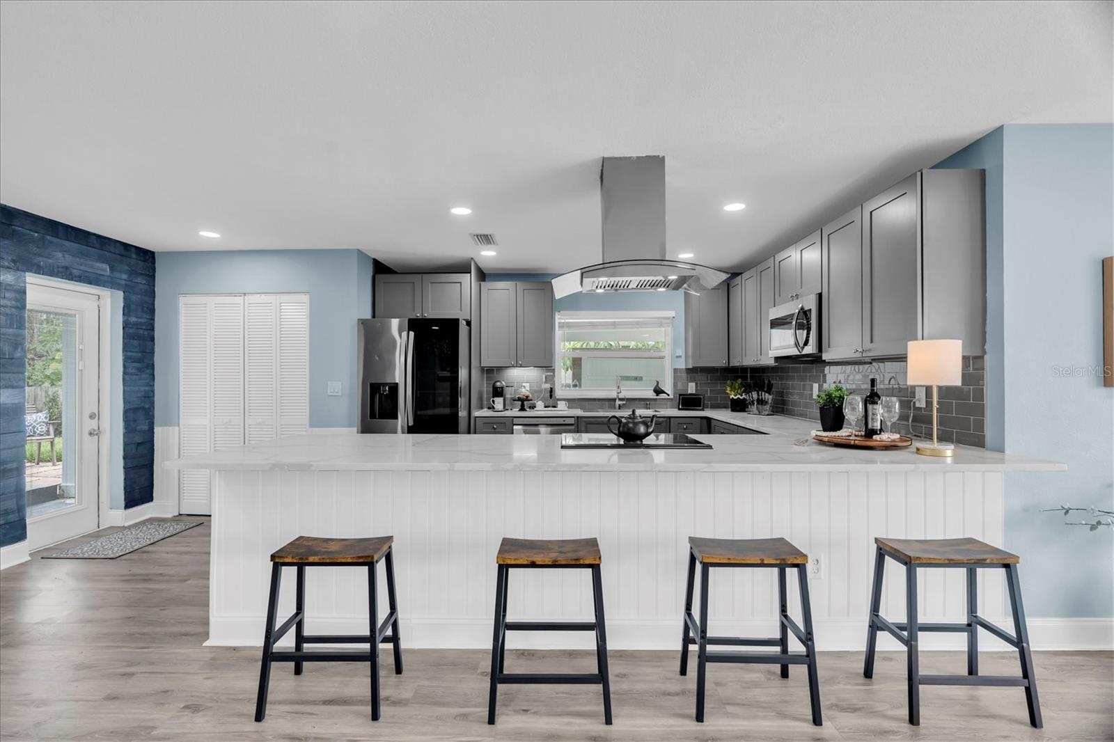 Large quartz peninsula provides additional prep space and casual seating while keeping the kitchen open to the living areas.