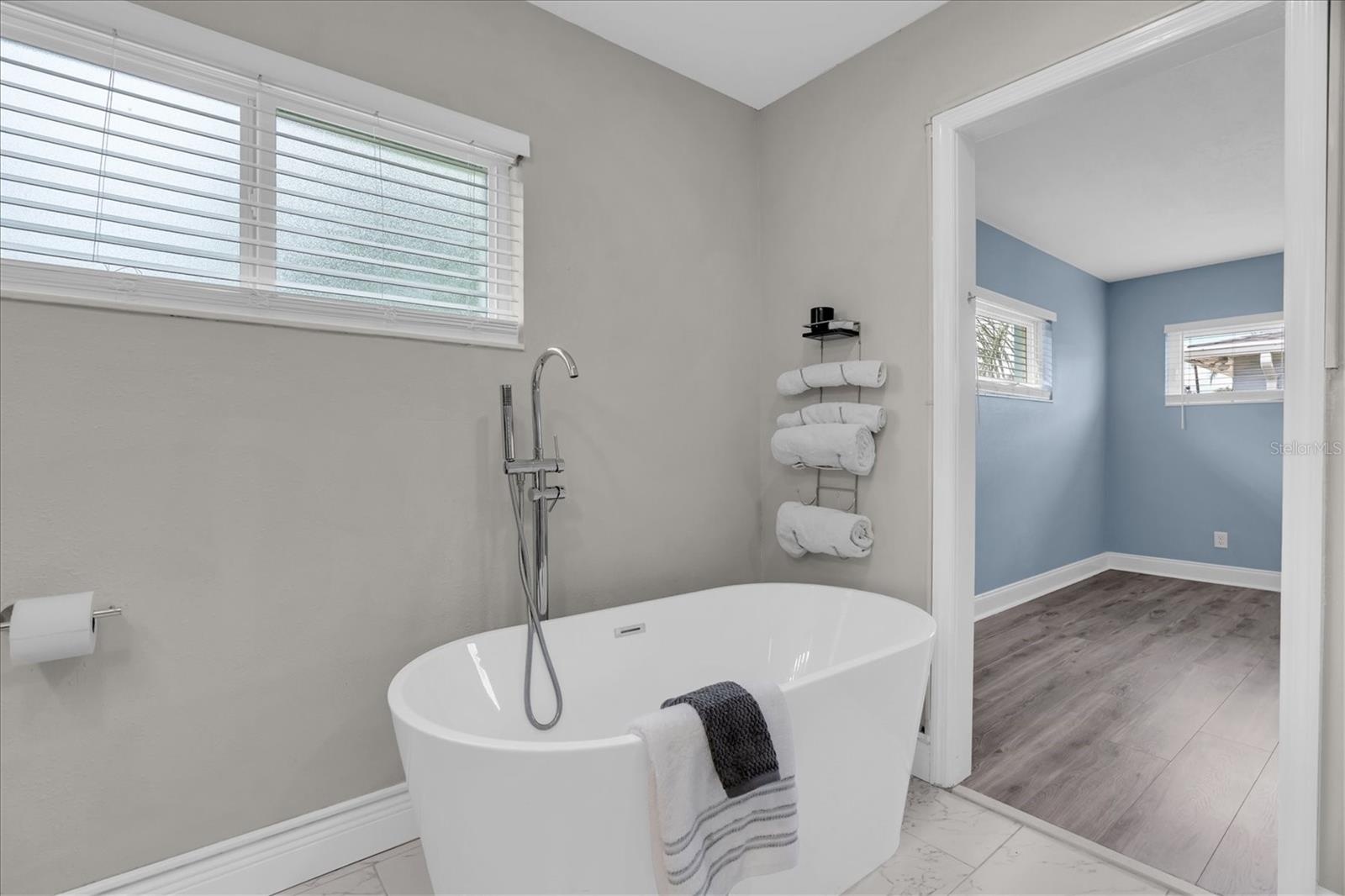 Freestanding clawfoot soaking tub and black iron fixtures complete the primary bath's modern coastal look.