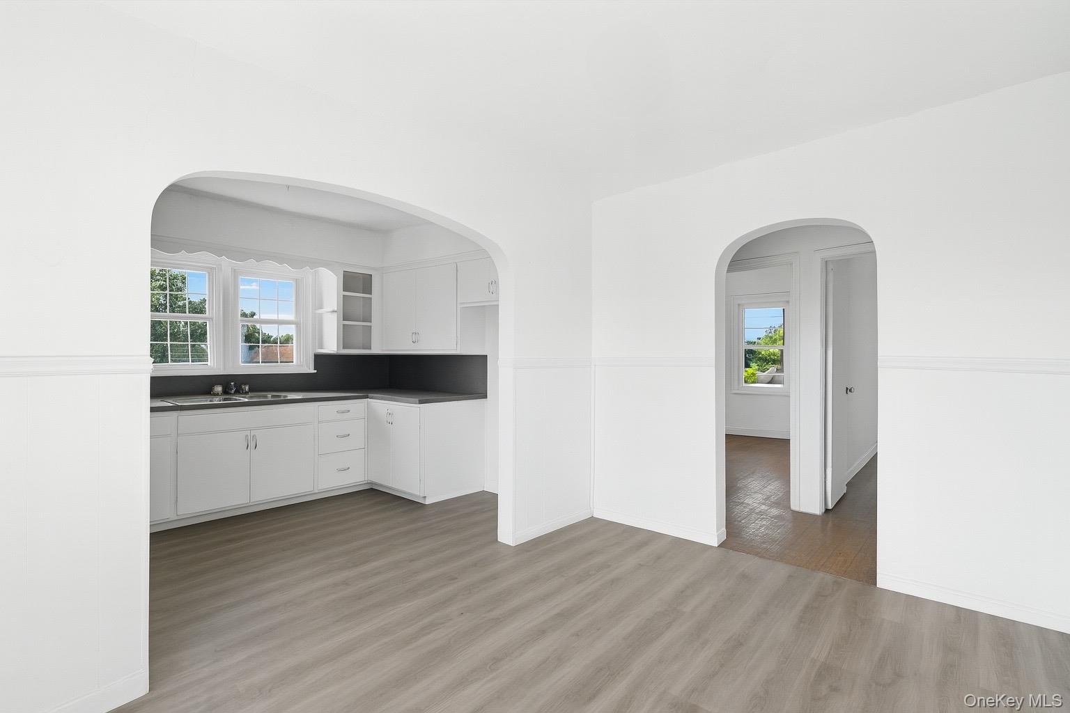 Kitchen featuring dark countertops, white cabinetry, plenty of natural light, and light wood-style flooring