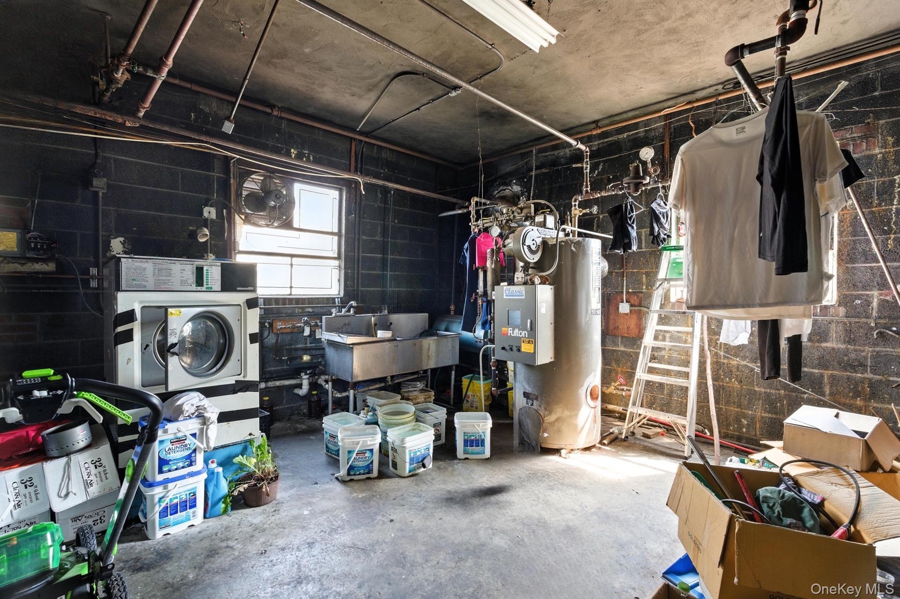Basement featuring concrete block wall, gas water heater, washer / clothes dryer, and plenty of natural light