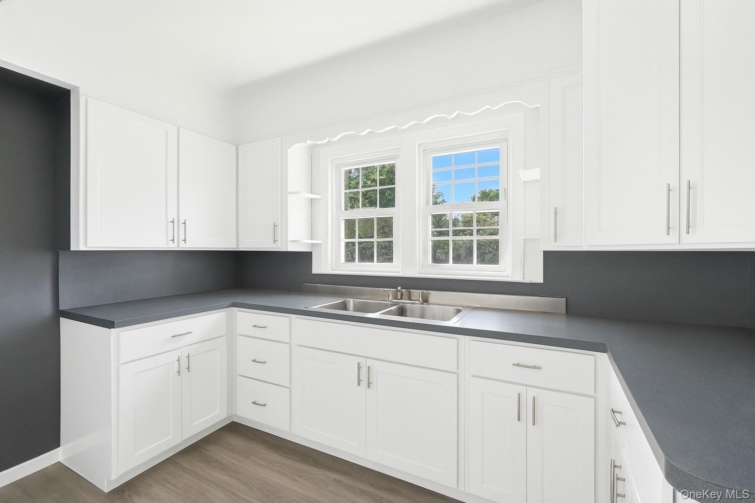 Kitchen featuring white cabinetry, dark countertops, and light wood-type flooring