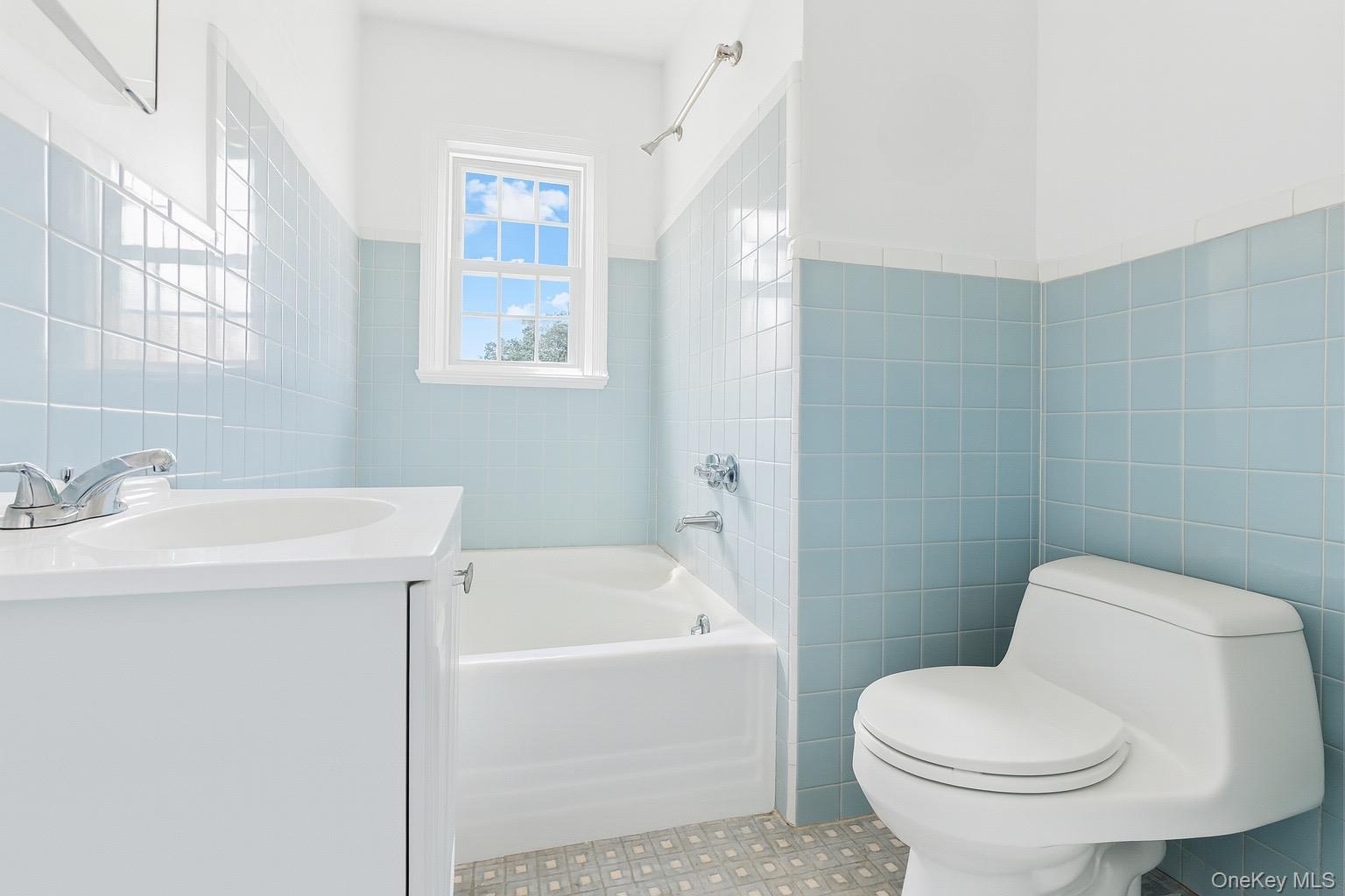 Bathroom featuring tile walls, vanity, shower / washtub combination, and wainscoting