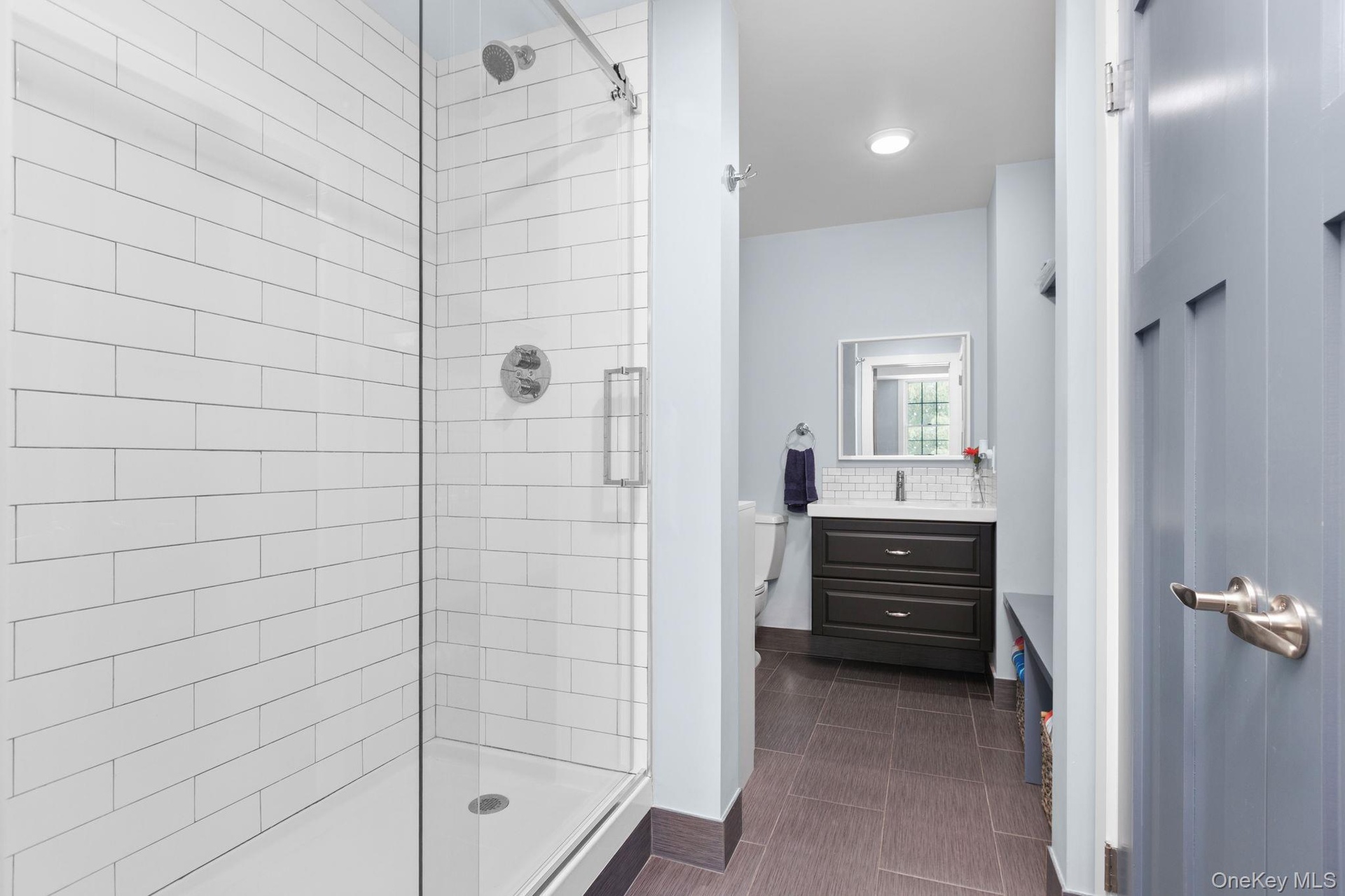Conveniently located just steps from the family room, this beautifully appointed bathroom features a walk-in shower with classic subway tile and a fra