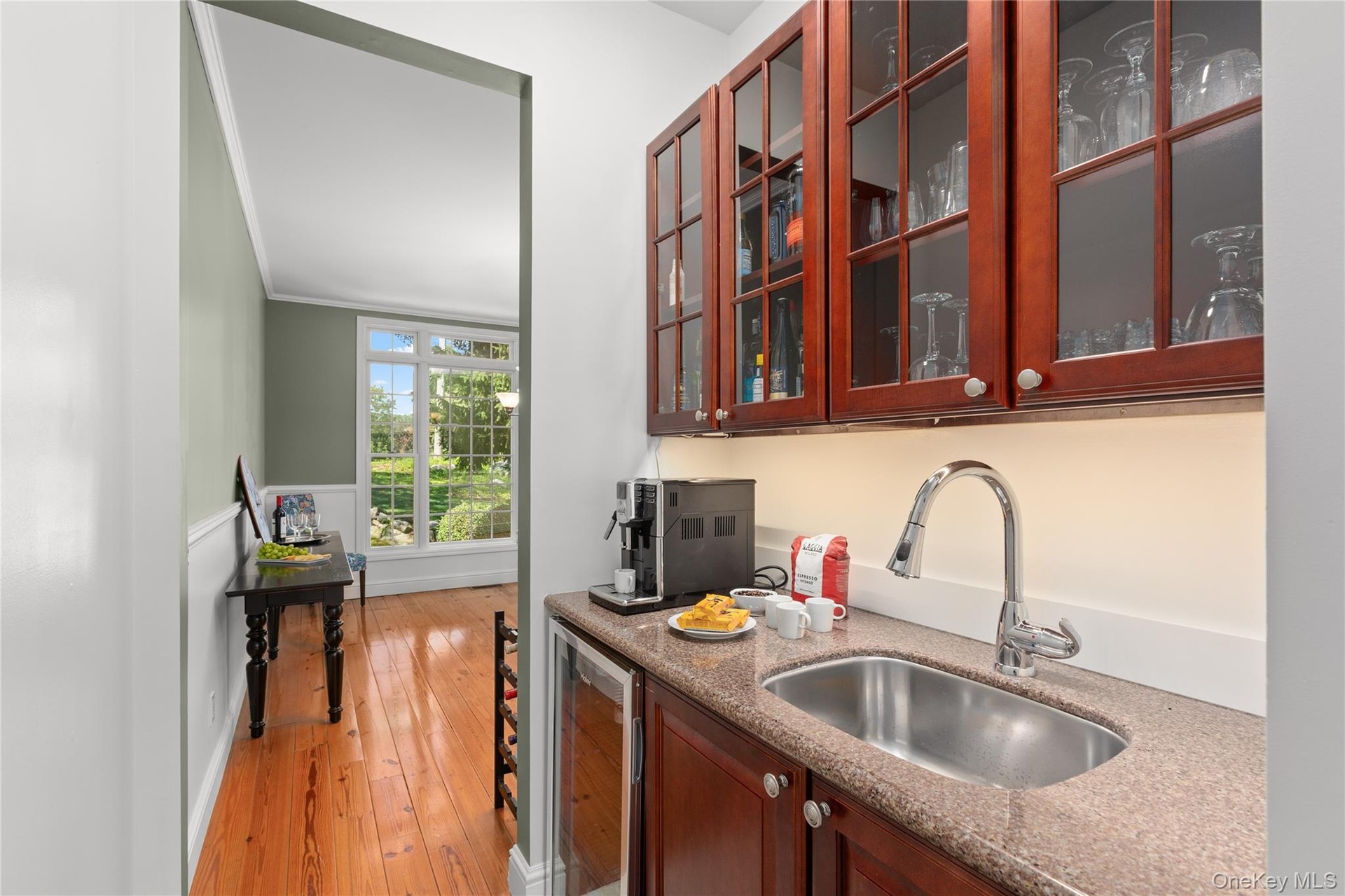 A beautifully appointed butler’s pantry featuring rich cabinetry and a dedicated coffee bar seamlessly connects the kitchen to the formal dining room,