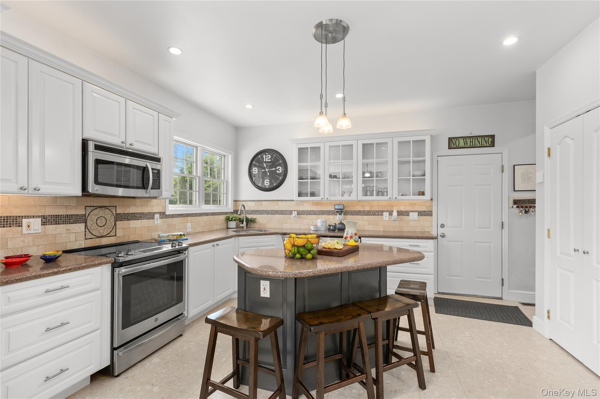 The heart of the home, this beautifully appointed kitchen features crisp white Shaker-style cabinetry with elegant glass-front displays, stainless ste