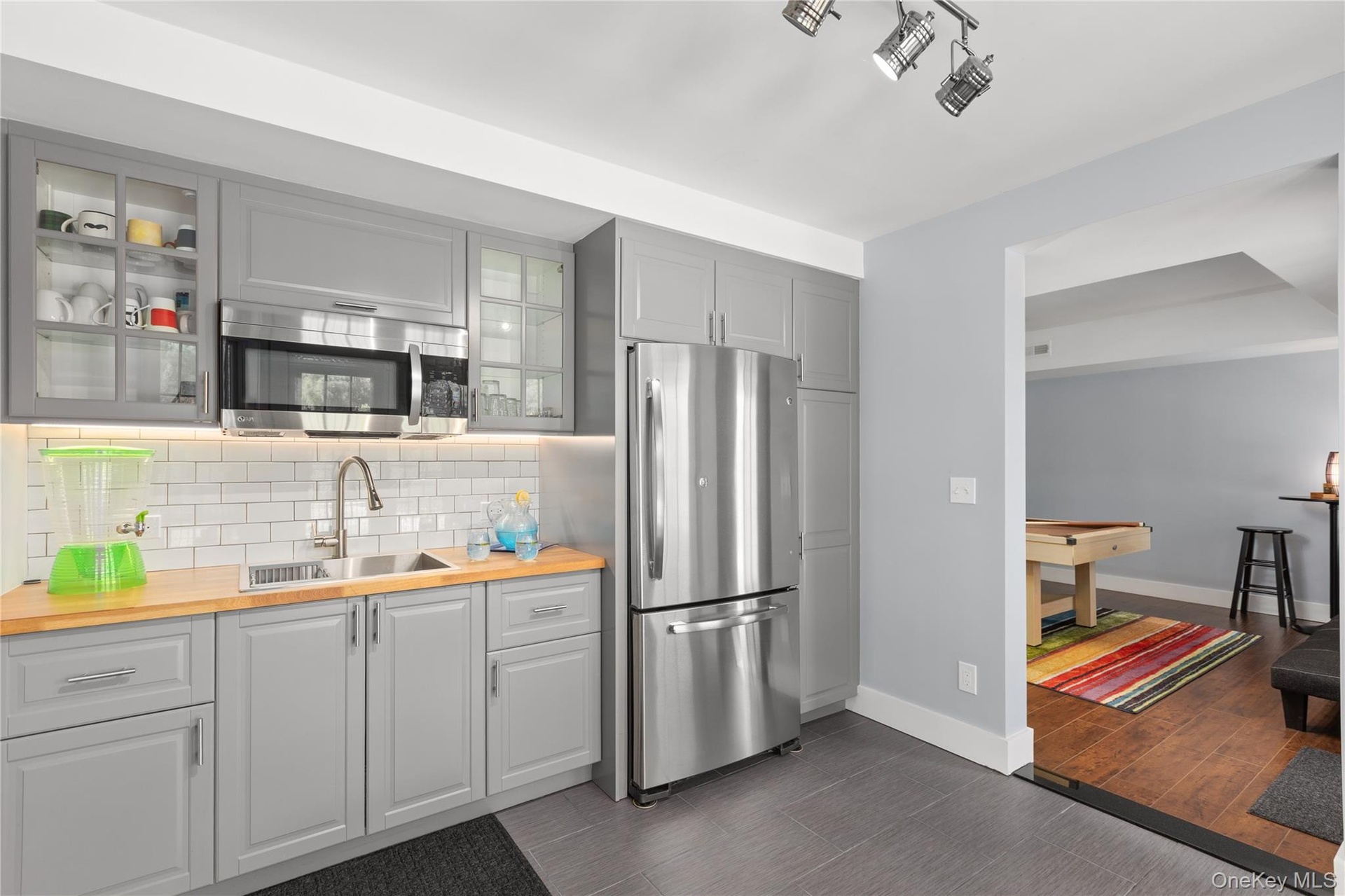 Adding to the versatility and convenience of the lower-level living space, a thoughtfully appointed kitchenette features stylish gray-toned and glass-