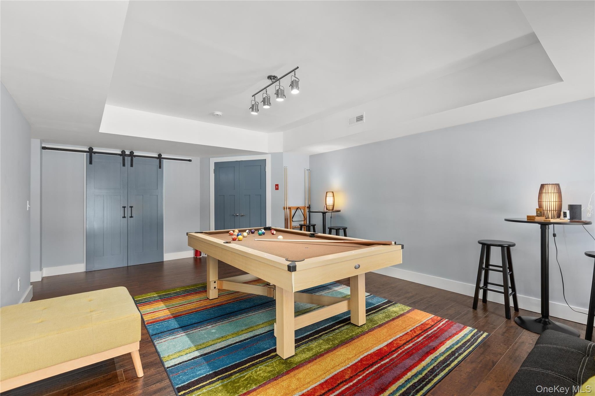 Designed for fun and entertainment, this spacious game room features an elegant tray ceiling, task lighting, and warm wood-toned flooring, with ample 