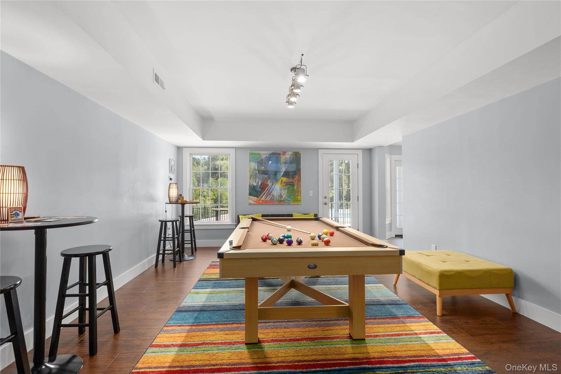Abundant natural light streams through the large window and glass doors, enhancing the game room’s bright, inviting atmosphere and creating a welcomin