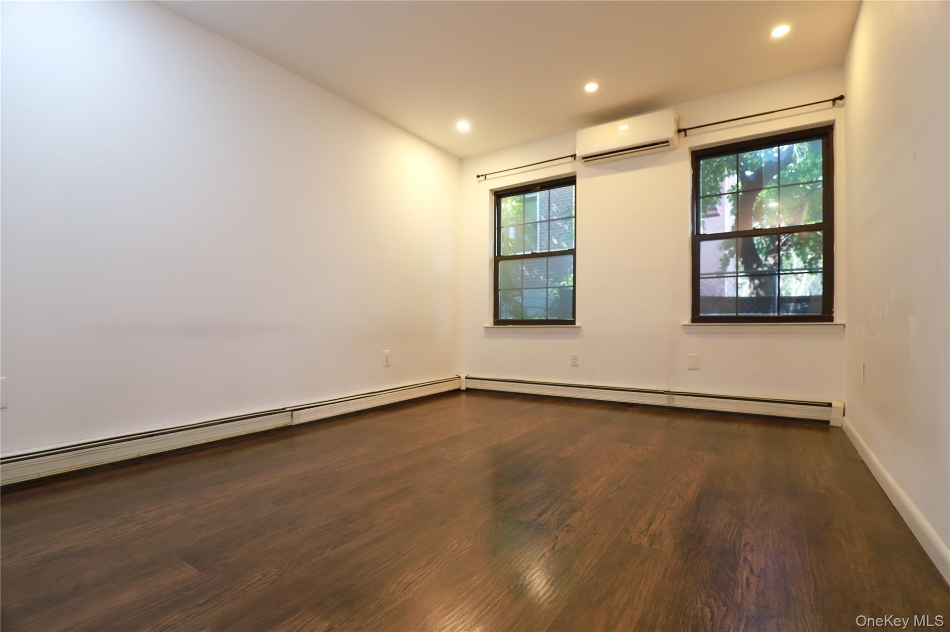 Hardwood flooring, recessed lighting, two double-hung windows, and a wall-mounted mini-split system