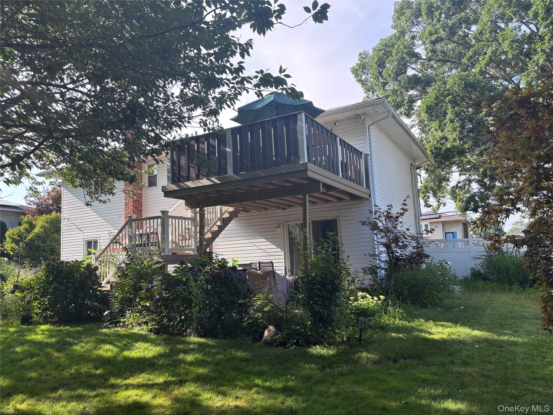 Two-story deck with wood railing, leading to a ground-level patio