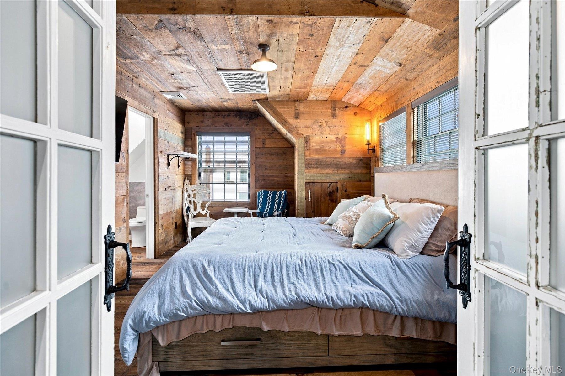 Primary bedroom with reclaimed wood-paneled walls and ceiling