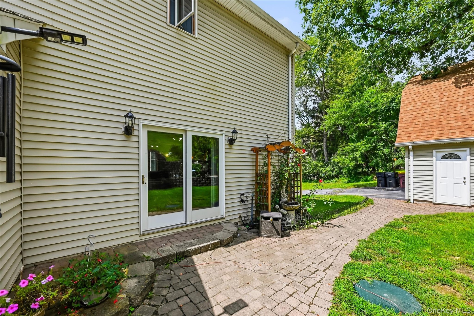Back of home with paver patio and walkway leading to the detached garage.