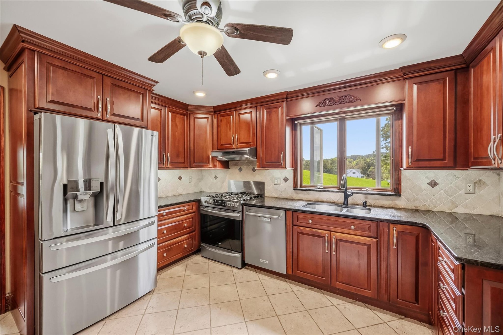Kitchen with wood cabinetry, granite countertops, tile backsplash and stainless steel appliances.