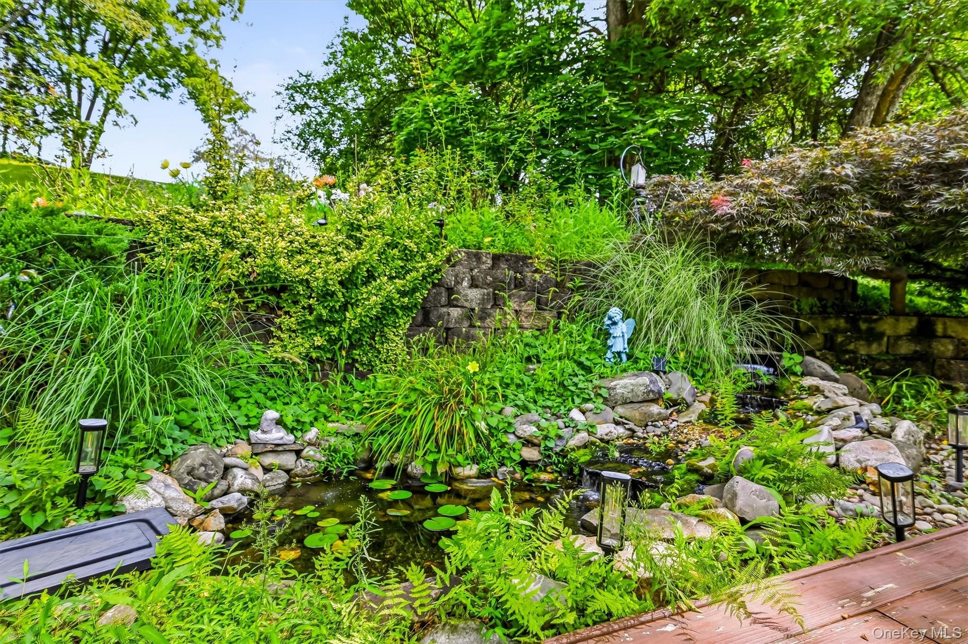 Landscaped backyard pond with a waterfall and surrounding gardens.