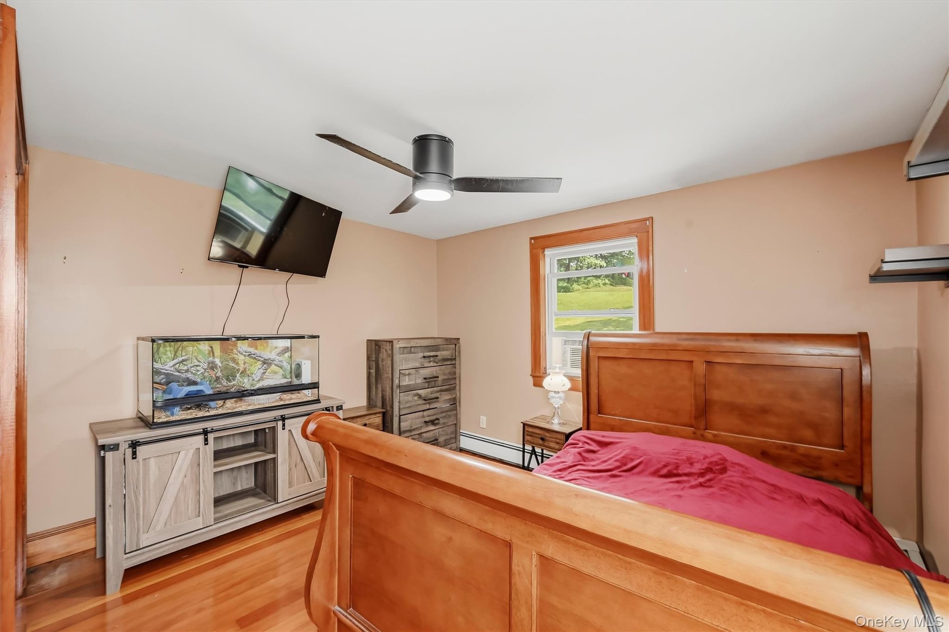 Bedroom with hardwood floors, wood trim and ceiling fan.