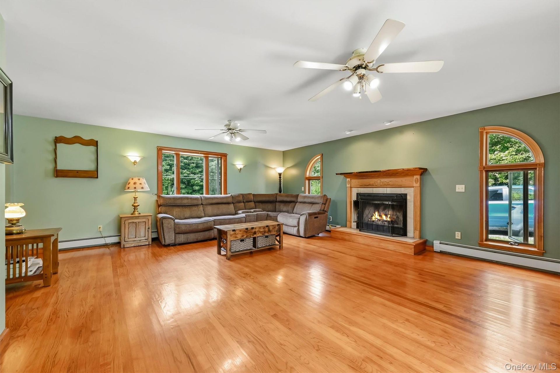 Spacious family room featuring hardwood floors, a fireplace, and distinctive arched windows.
