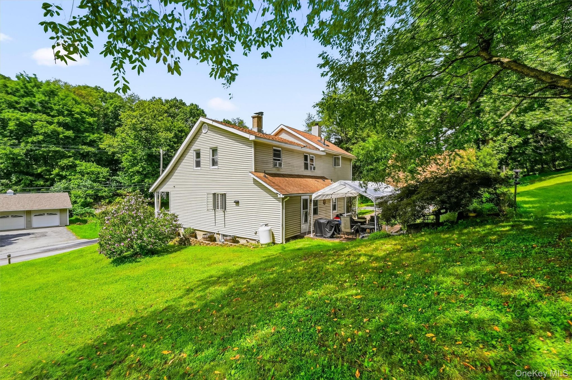 Rear exterior view with patio area, detached garage, and spacious yard.
