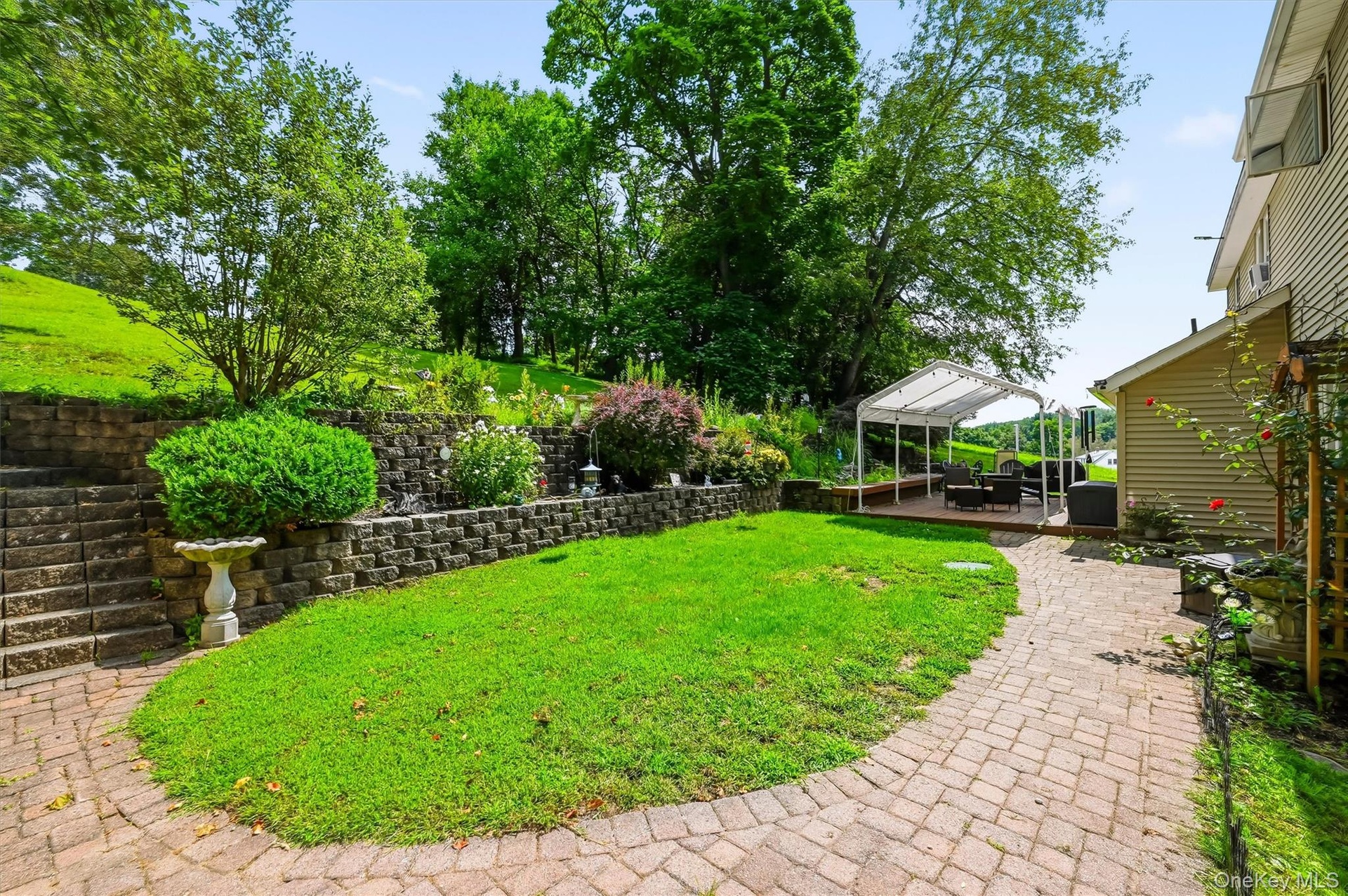 Landscaped backyard with paver walkways, retaining walls, and an outdoor seating area.