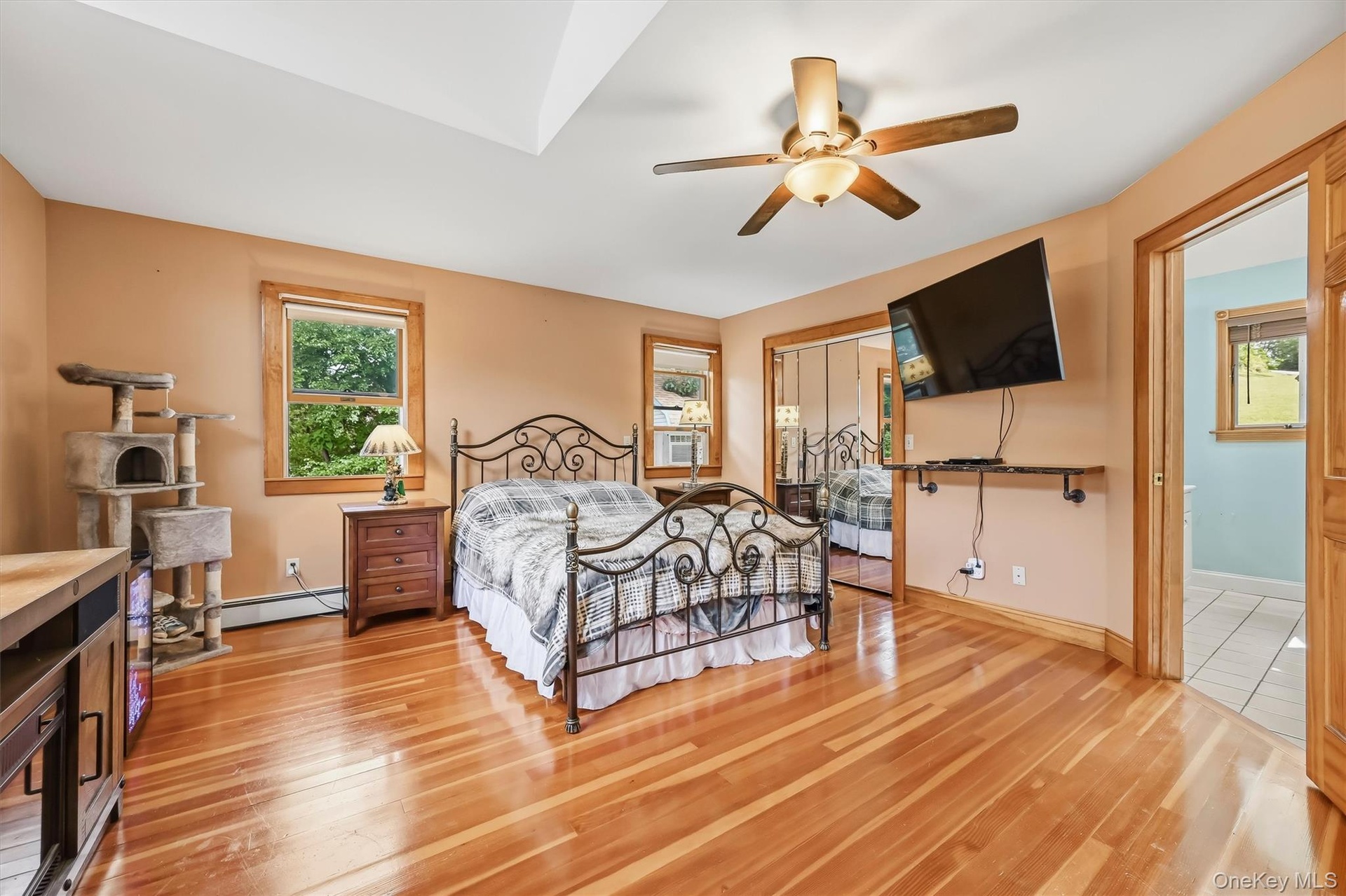 Primary bedroom with hardwood floors, vaulted ceiling, ample closet space and direct access to the private bathroom.