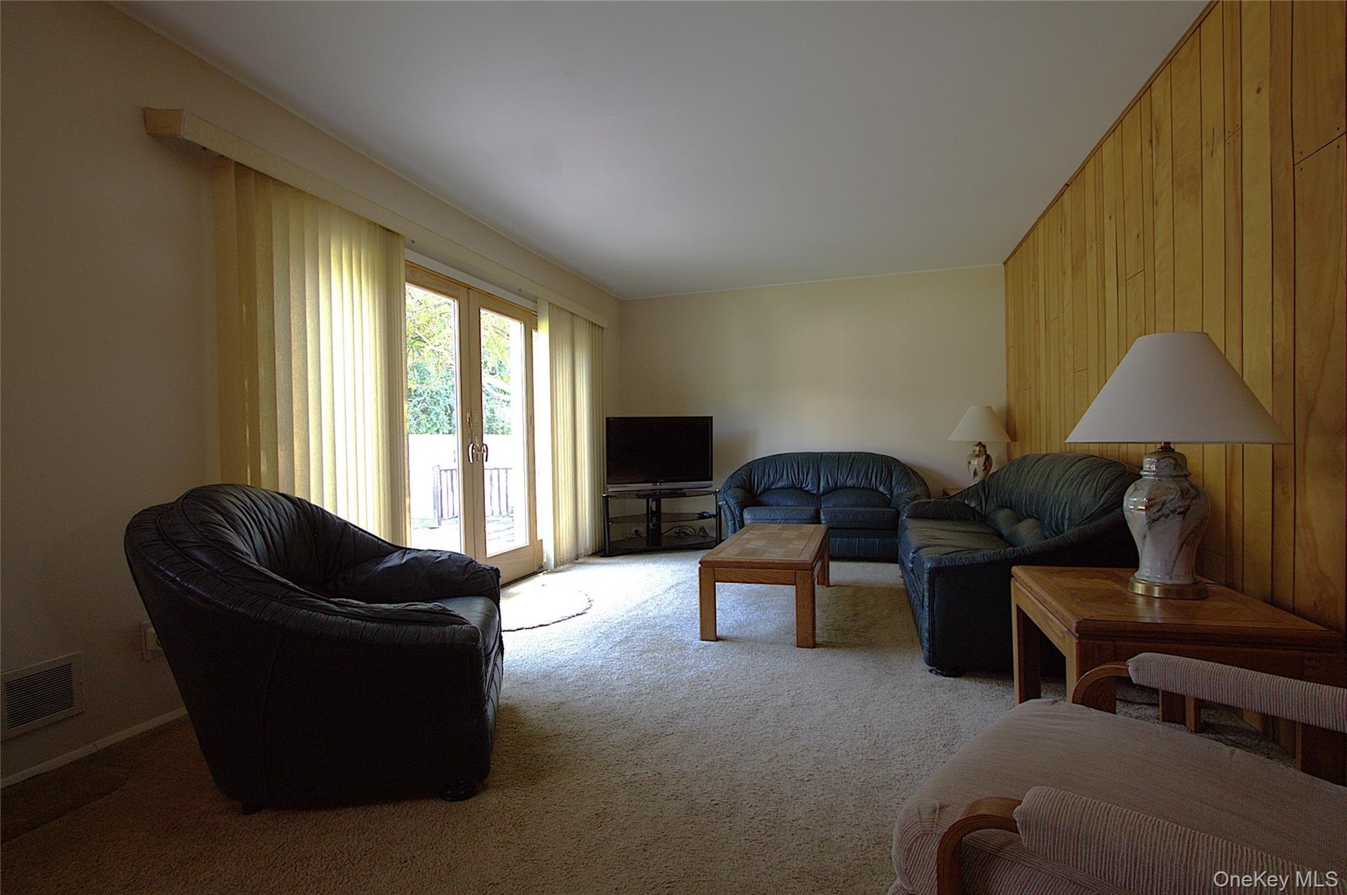 Wood accent wall, carpeted flooring, and glass-paneled sliding doors
