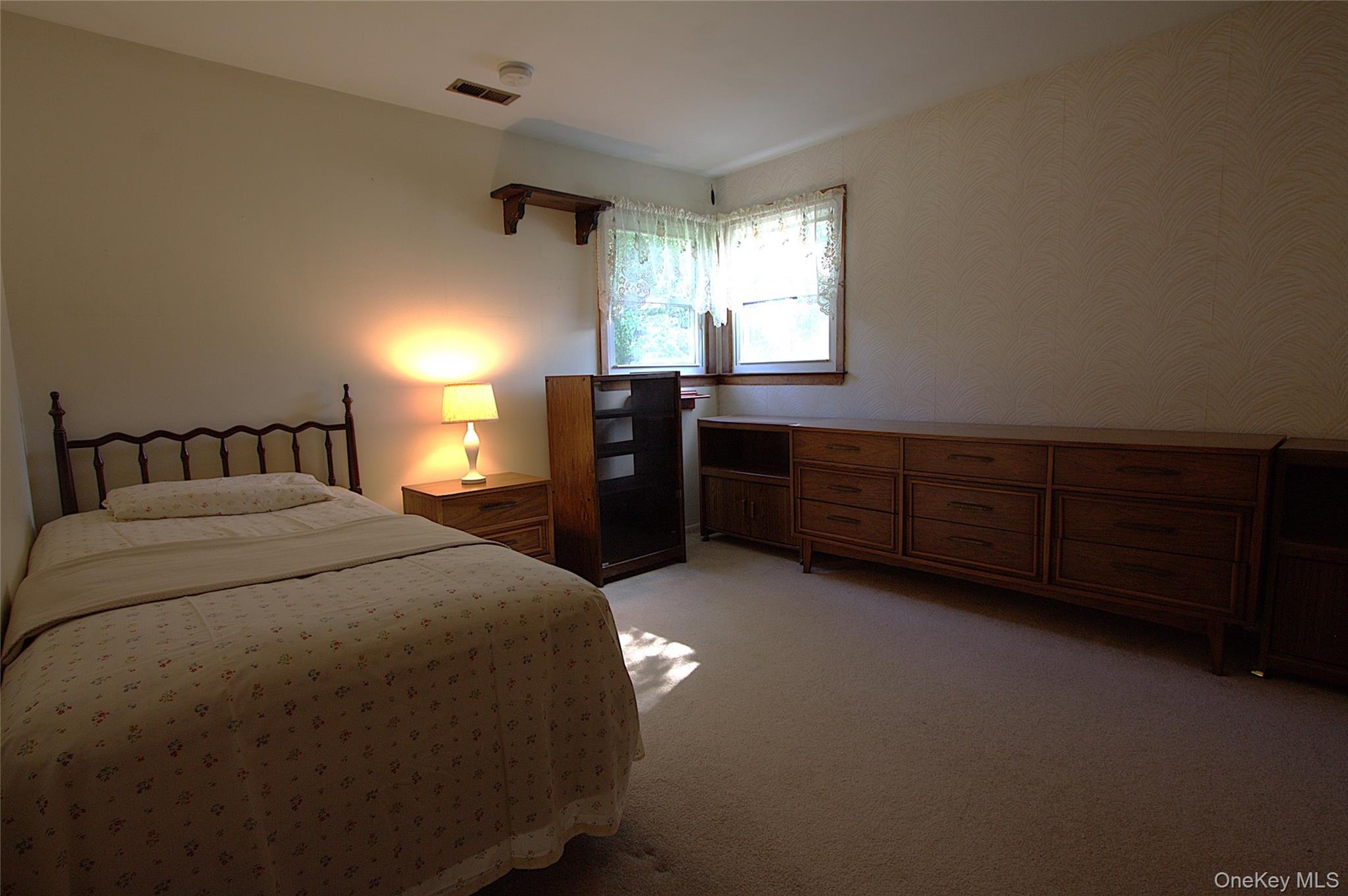 Carpeted flooring, window with natural wood trim, light-toned walls