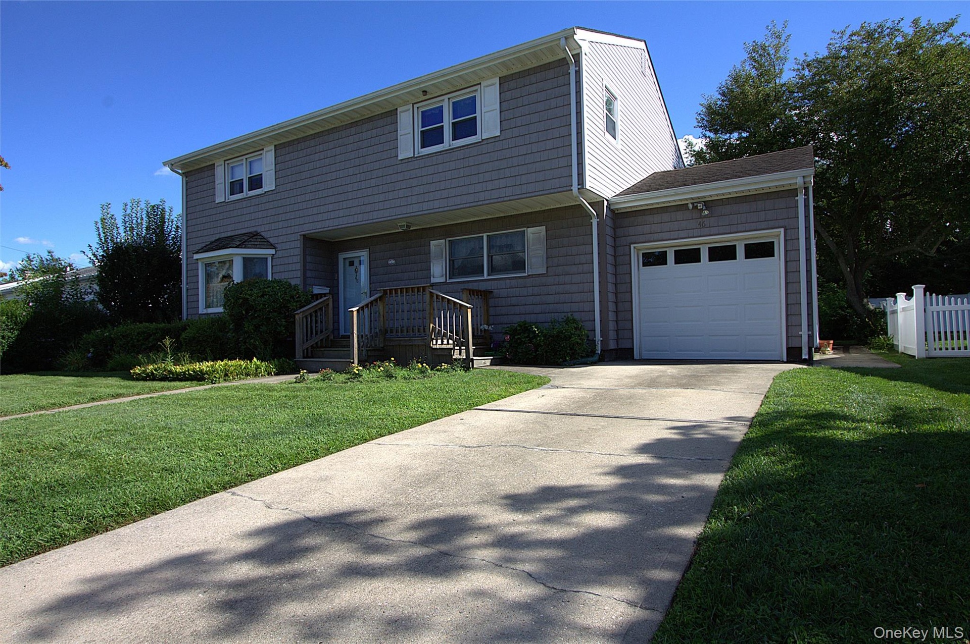 Two-story exterior with horizontal siding, attached garage with panel door, concrete driveway, and front lawn