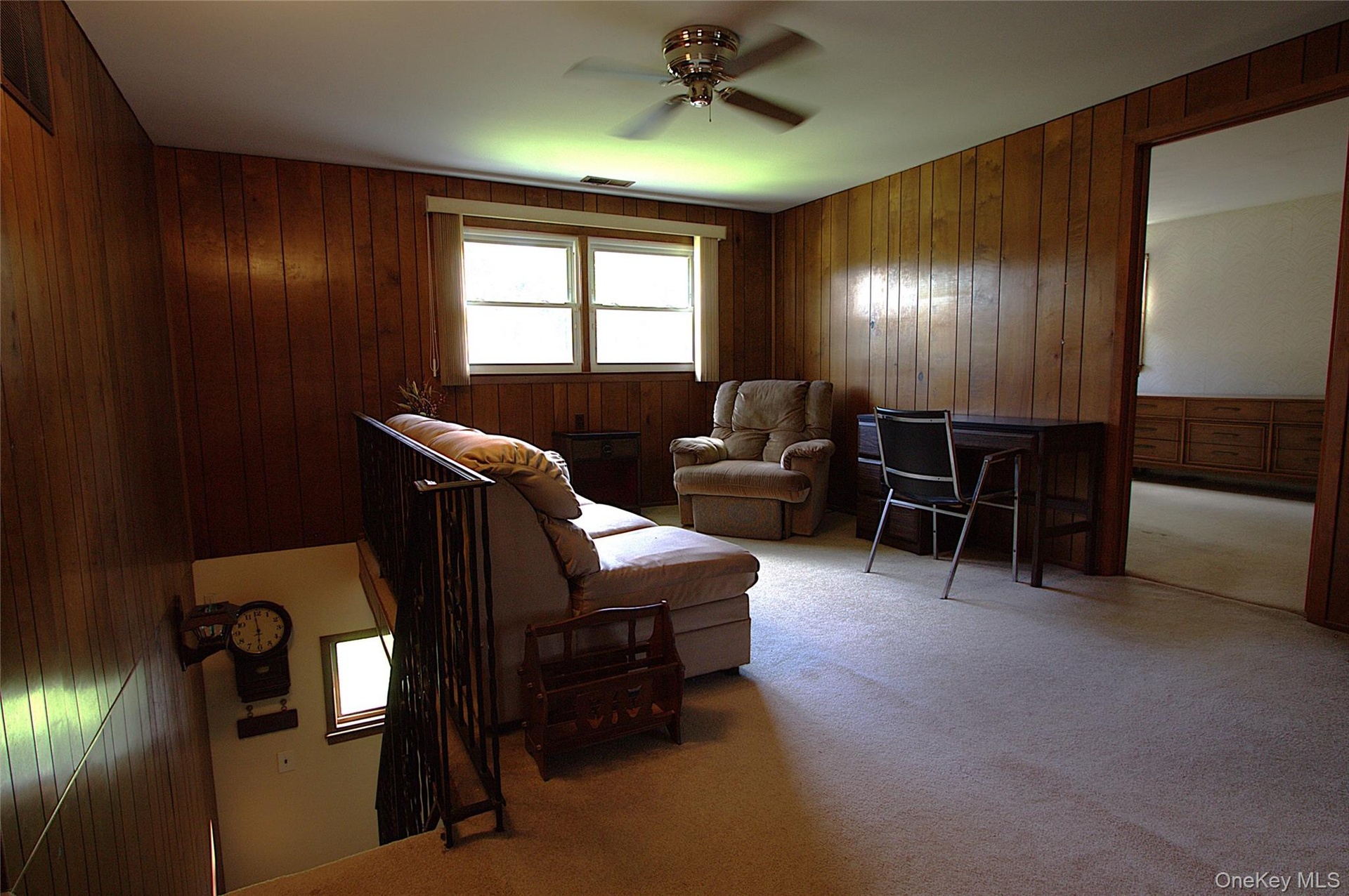 Wood-panel walls, carpeted flooring, and a ceiling fan with integrated lighting