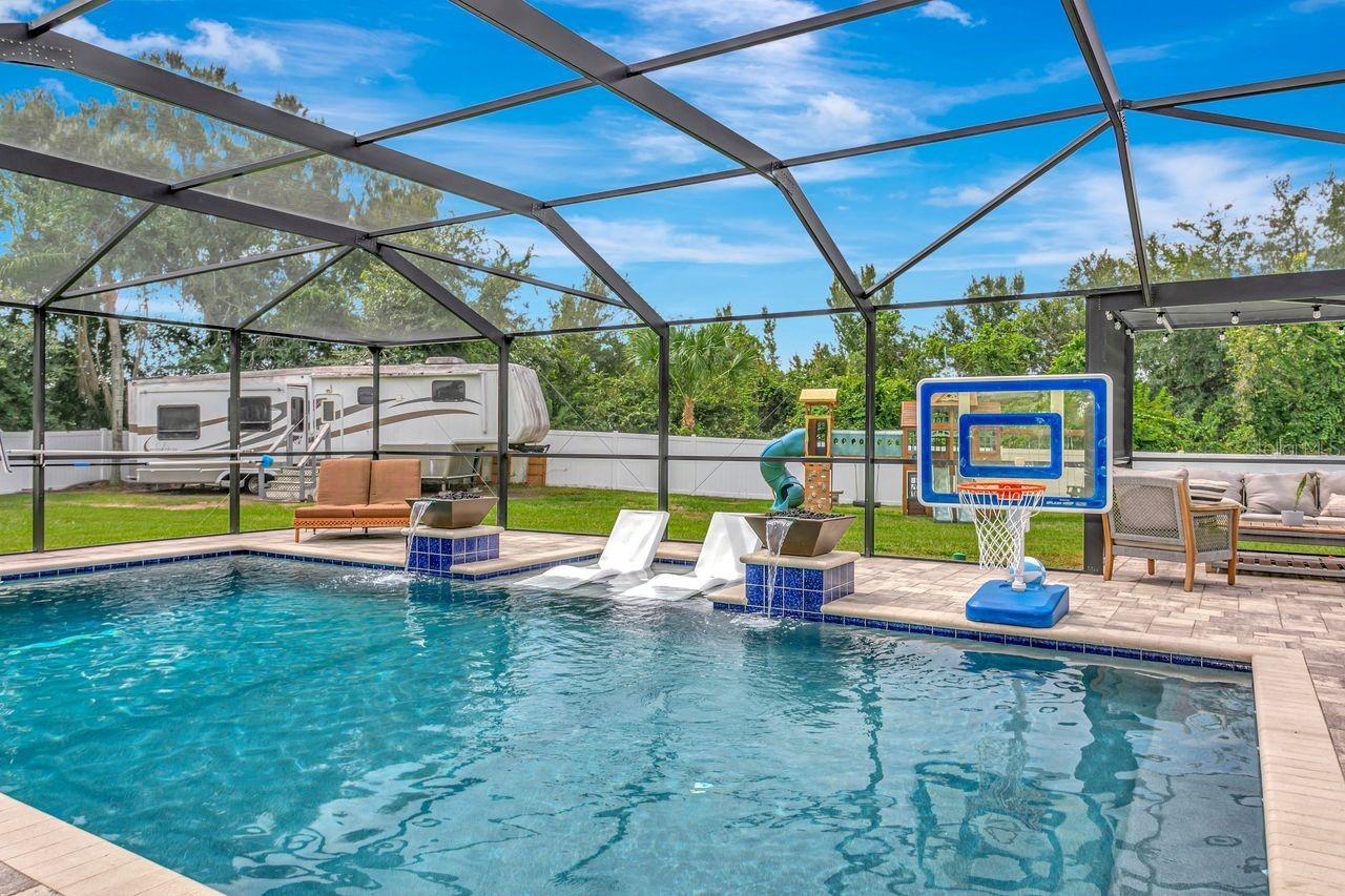 View of Outdoor Summer Kitchen; Expansive Covered Rear Lanai; Custom Pool with Sun Shelf, Fire and Waterfall feature; Pavered Floor; Additional Seatin