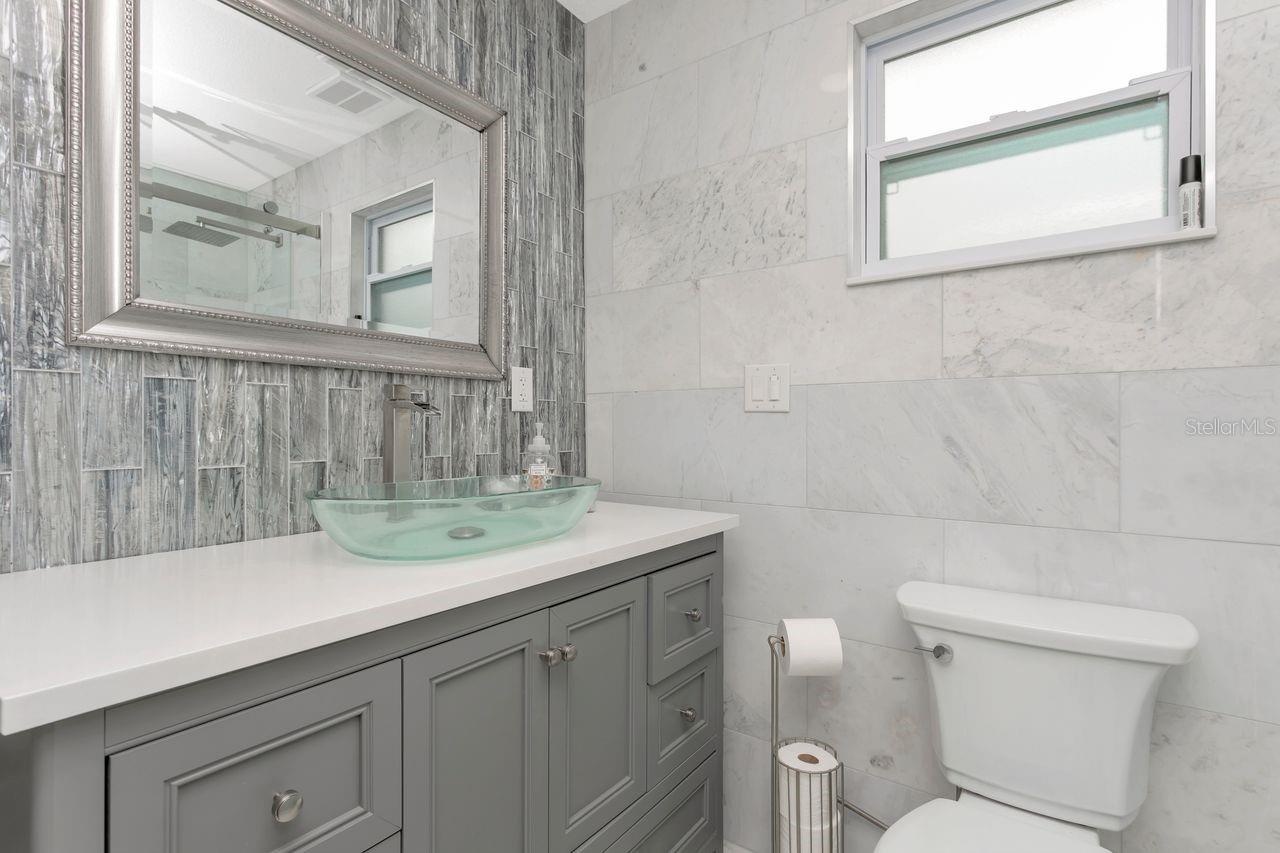 Remodeled Full "Pool Side" Bathroom with elevated fixtures, Shower with Tile to Ceiling and Recessed Decorative Niche; Statement Sink basin; Located o