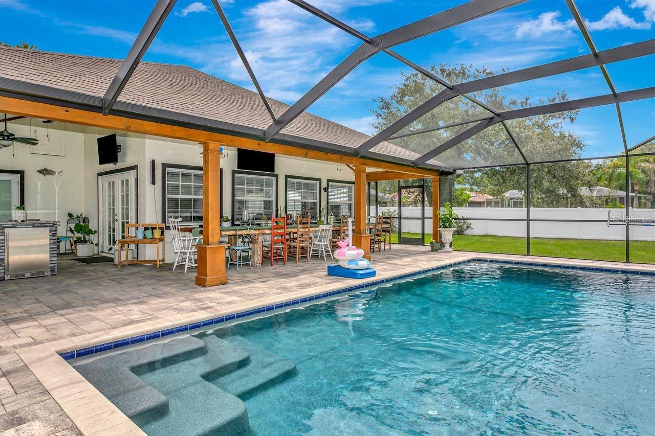 View of Outdoor Summer Kitchen; Expansive Covered Rear Lanai; Custom Pool with Sun Shelf, Fire and Waterfall feature; Pavered Floor; Additional Seatin