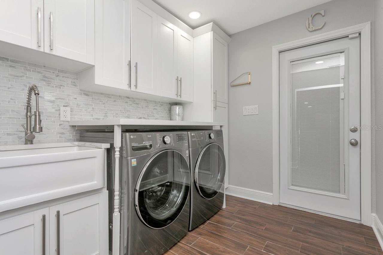 Inside Laundry Room upgraded with Front Load Washer/Dryer; LVP Flooring; White Cabinetry with upgraded hardware; Modern Utility Sink with Undermount S