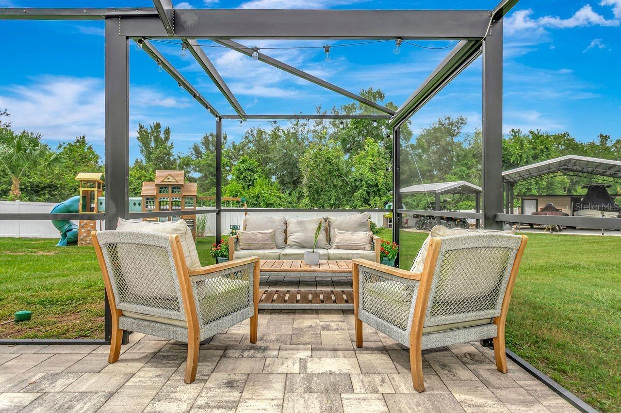 View of Outdoor Summer Kitchen; Expansive Covered Rear Lanai; Custom Pool with Sun Shelf, Fire and Waterfall feature; Pavered Floor; Additional Seatin