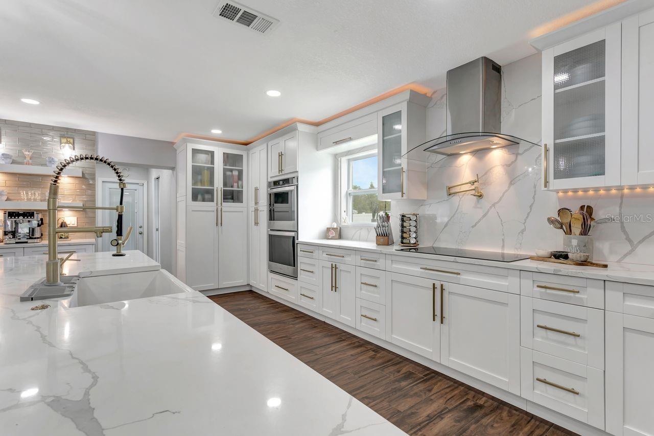 Remodeled Kitchen with upgraded custom cabinets with crown molding trim and lighting; elevated hardware and fixtures; quartz countertops; two-tone Cab