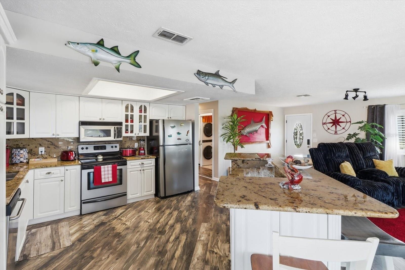 Bright kitchen featuring white cabinetry, extensive countertops, and stainless appliances.
