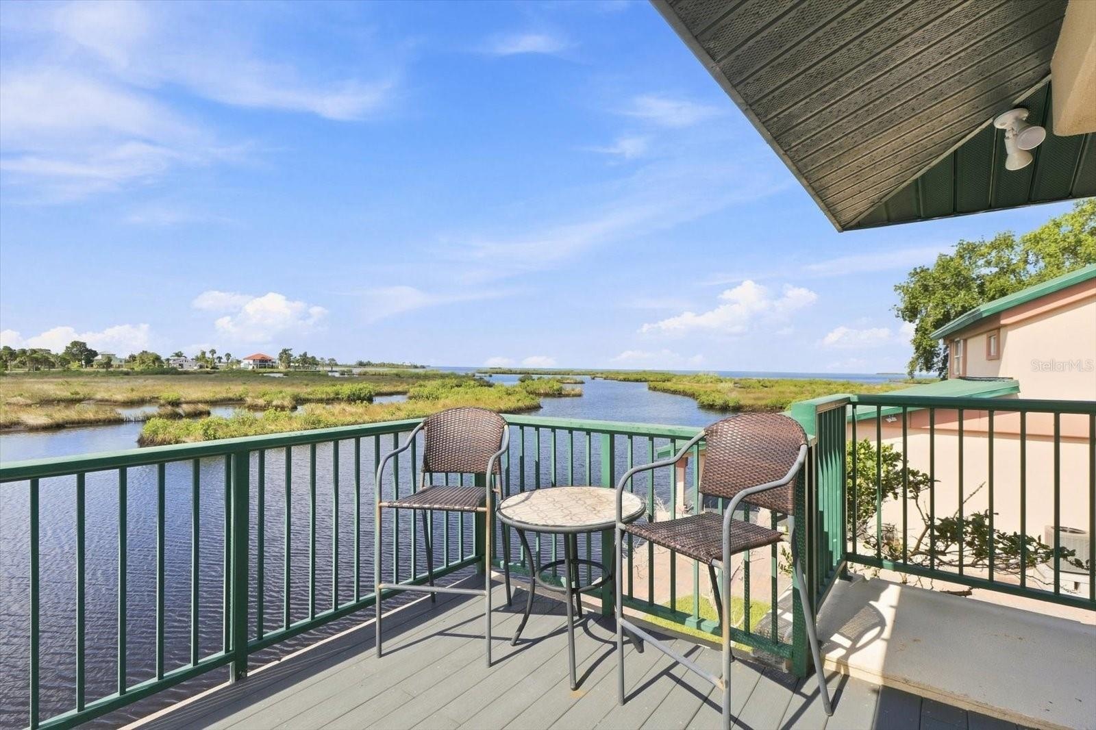 Balcony seating overlooking the water and natural coastal landscape.