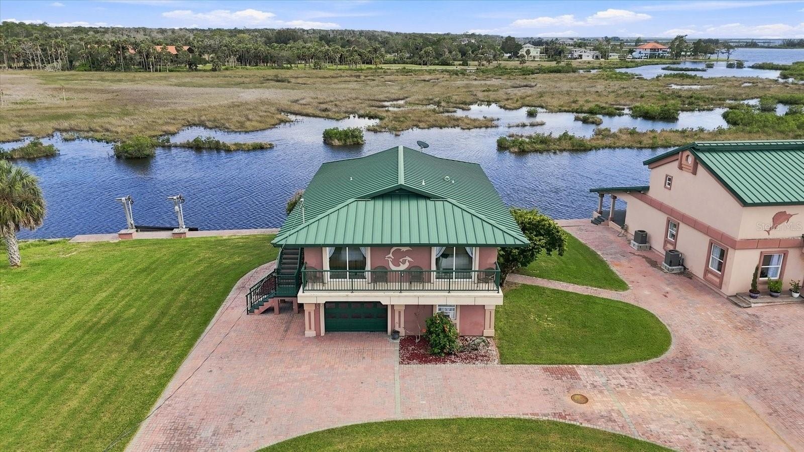Elevated aerial showing the residence positioned directly along the waterfront.