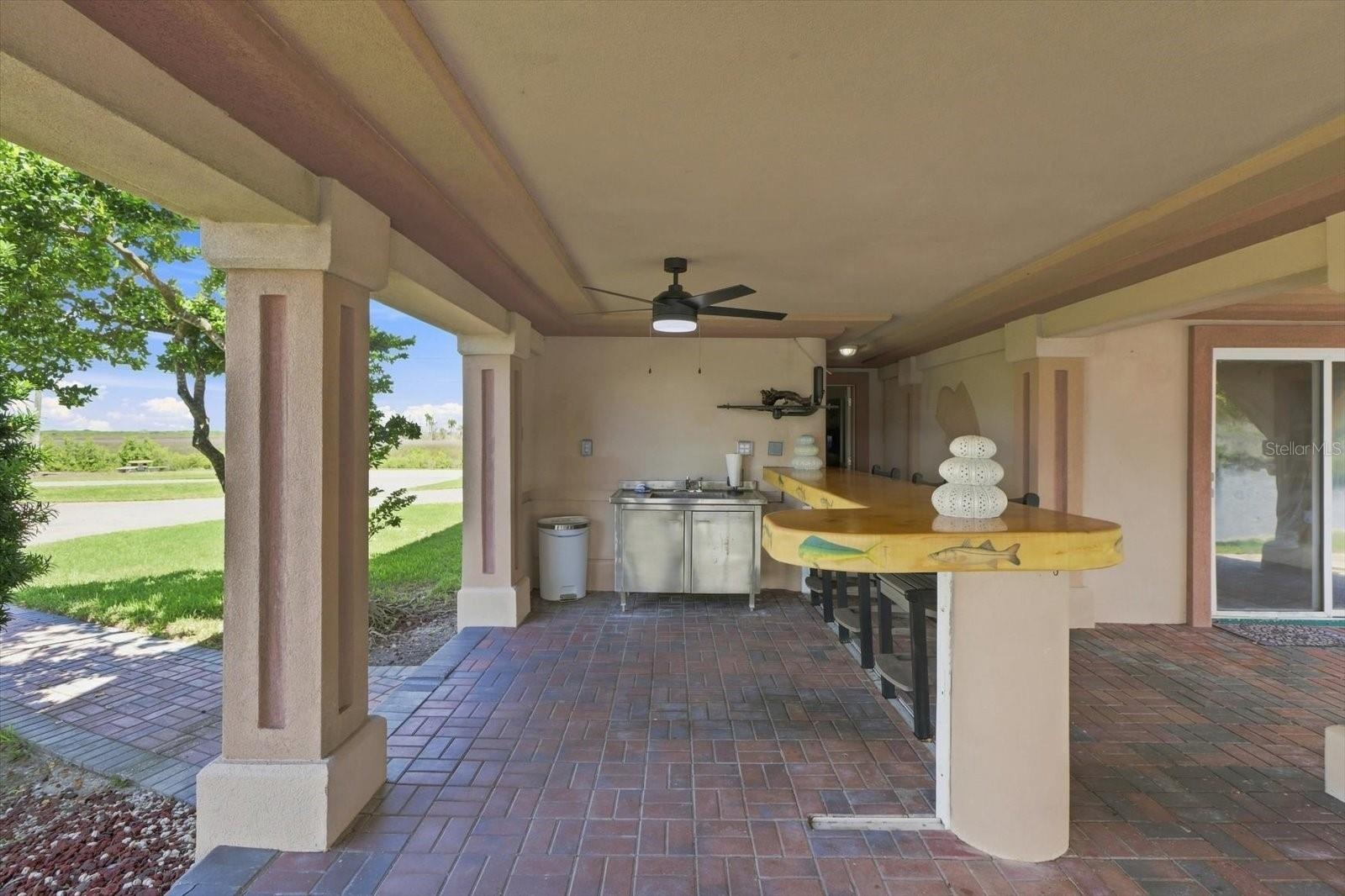 Wide view of the covered bar and adjoining outdoor living space.