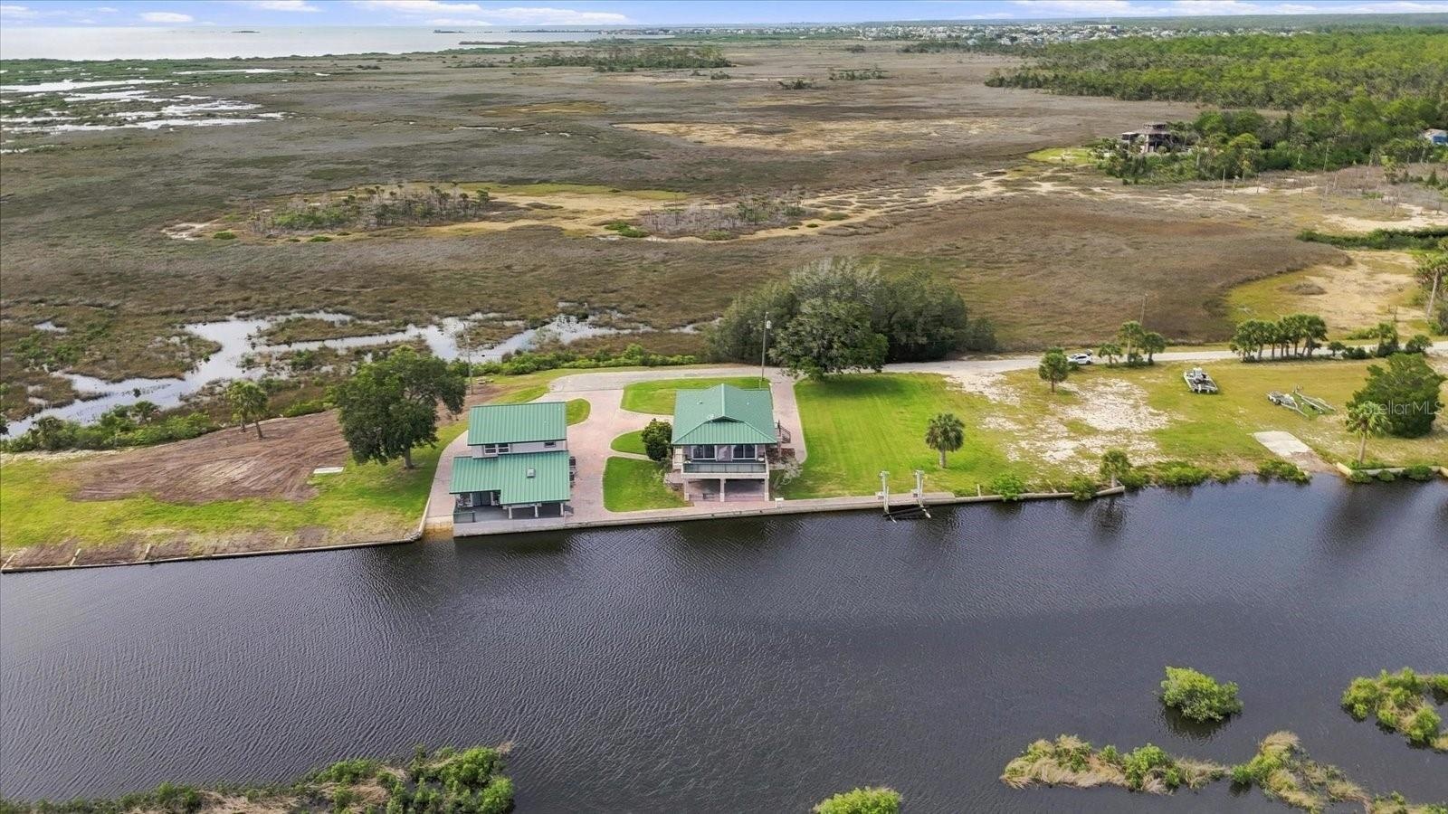 Wide aerial illustrating the property's waterfront position within the surrounding coastal environment.