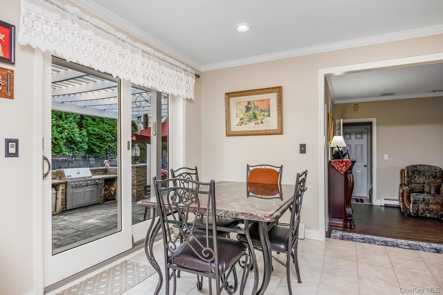Sliding glass doors opening to a paver patio with a built-in grill station and a pergola