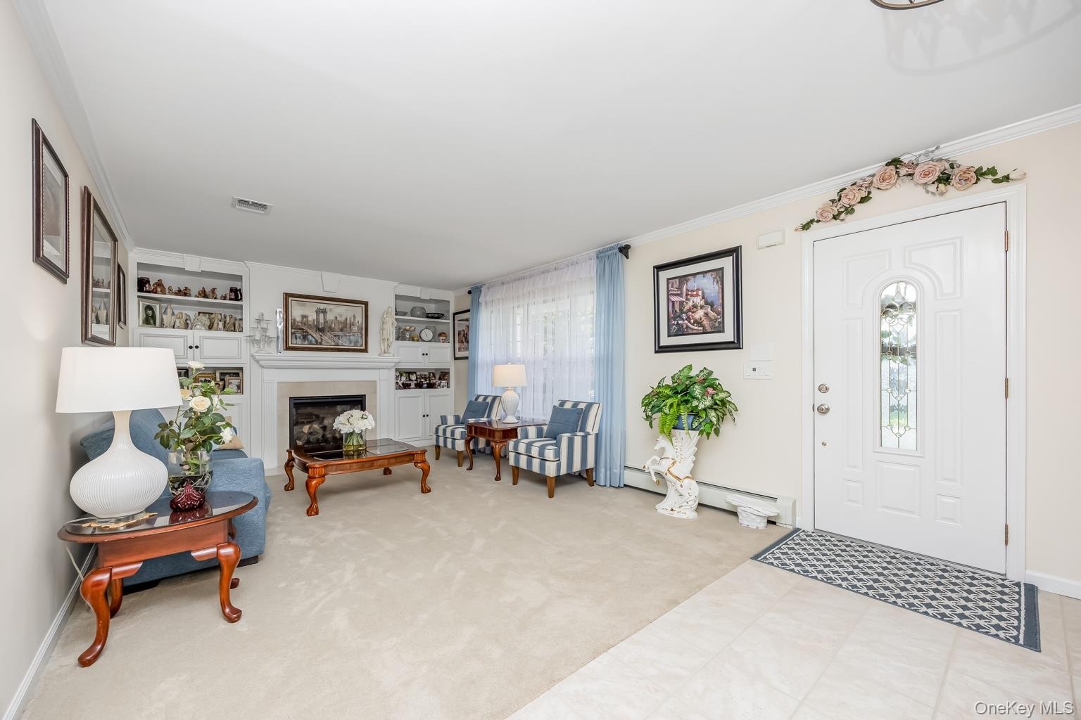 Recessed fireplace with a light-toned surround, built-in shelving, and light-toned wall-to-wall carpeting