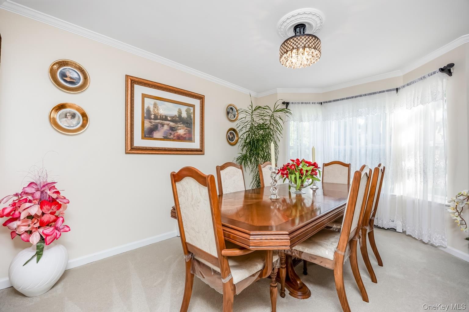 Recessed lighting fixture with decorative ceiling medallion, bay window with sheer curtains, and light neutral wall paint
