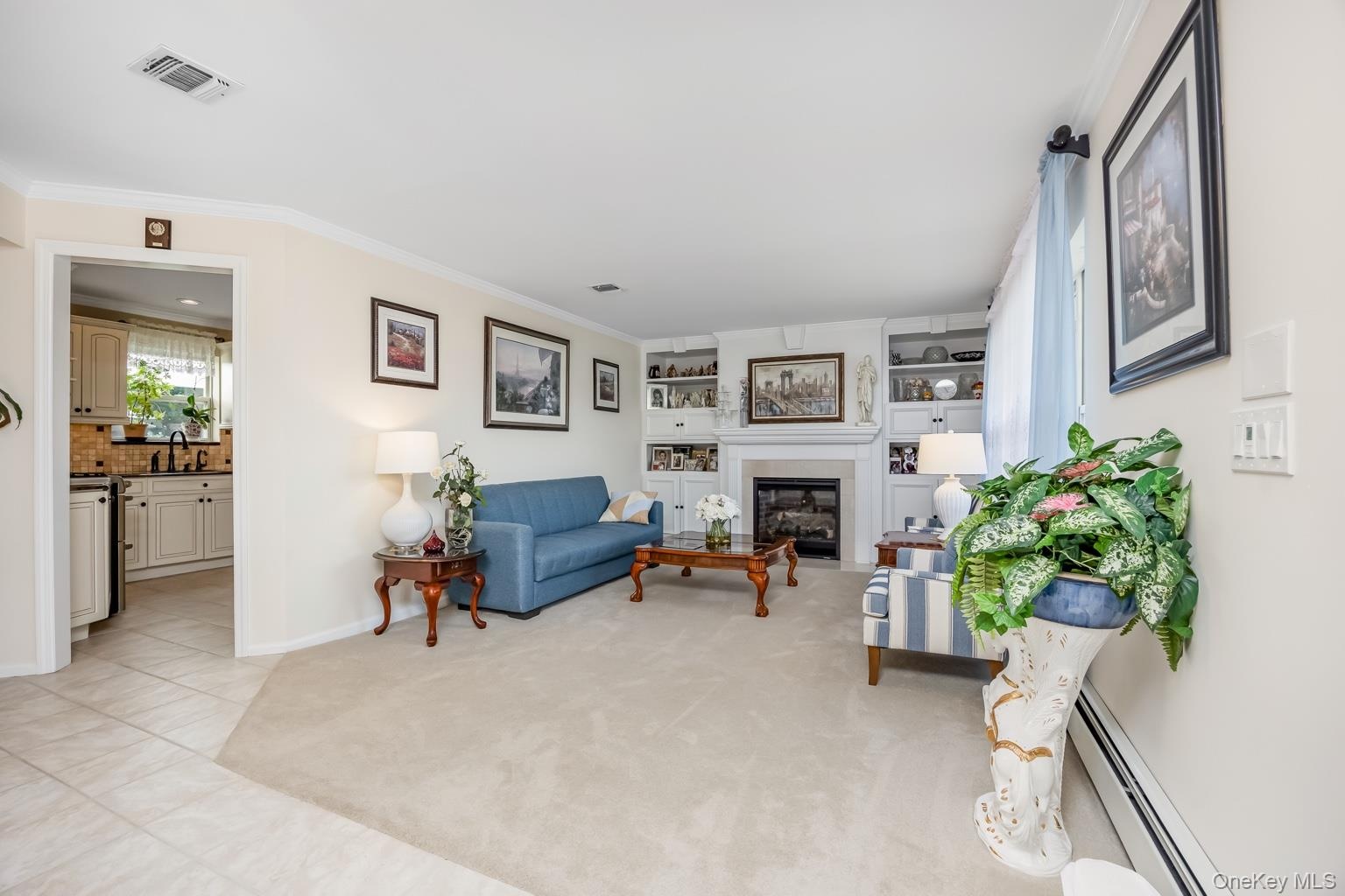 Living space featuring a built-in fireplace, custom shelving, crown molding, and carpeted flooring